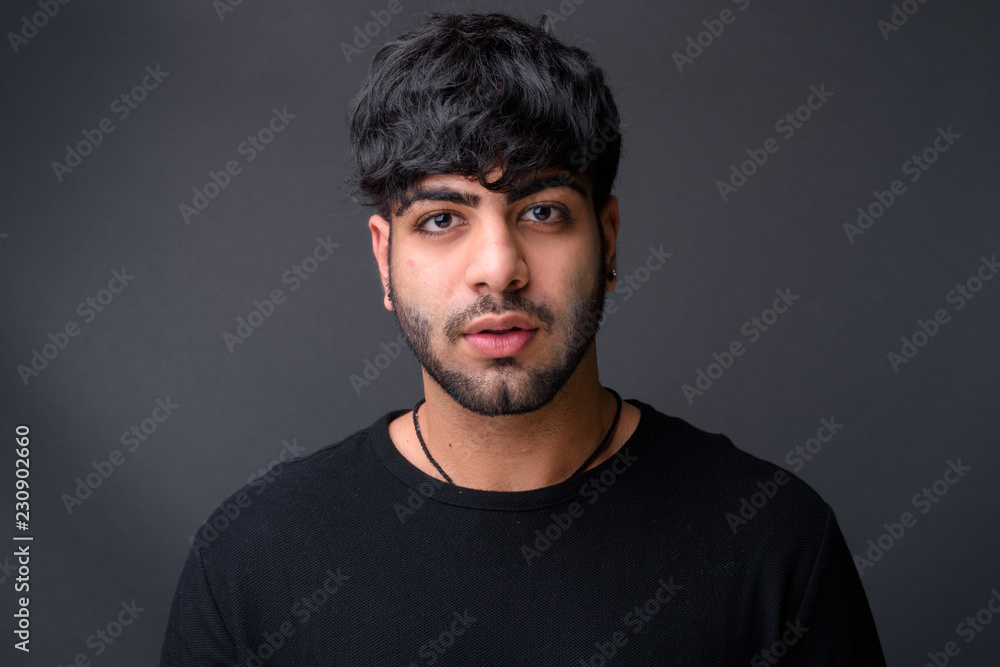 Young handsome Indian man against gray background