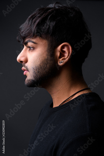 Young handsome Indian man against gray background