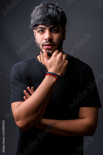 Young handsome Indian man against gray background