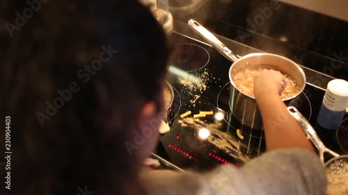 Over the shoulder shot of woman cooking in messy kitchen