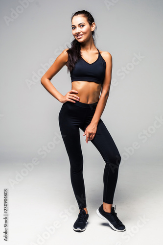 Full body portrait of a slim fitness woman dressed in a black sportswear isolated on white background.