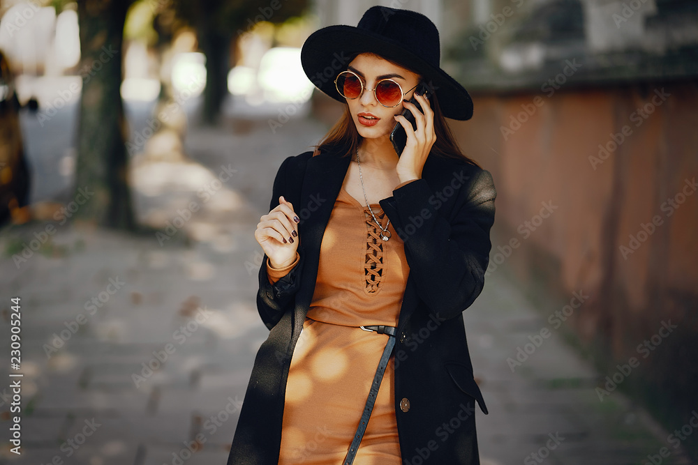 stylish girl walking through the city while using her phone