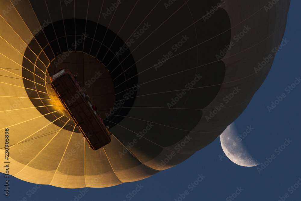 Fototapeta premium View from bellow a colorful hot air ballloon near the moon with beautiful blue sky in background