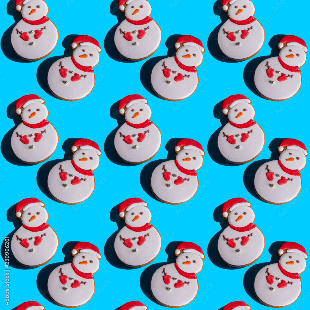 Seamless background with gingerbread in the shape of a snowman on a vivid blue background.Hard shadows.Abstract Christmas art background. Minimal print concept. Flat lay food Seamless background with gingerbread in the shape of a snowman on a vivid blue background.Hard shadows.Abstract Christmas art background. Minimal print concept. Flat lay food