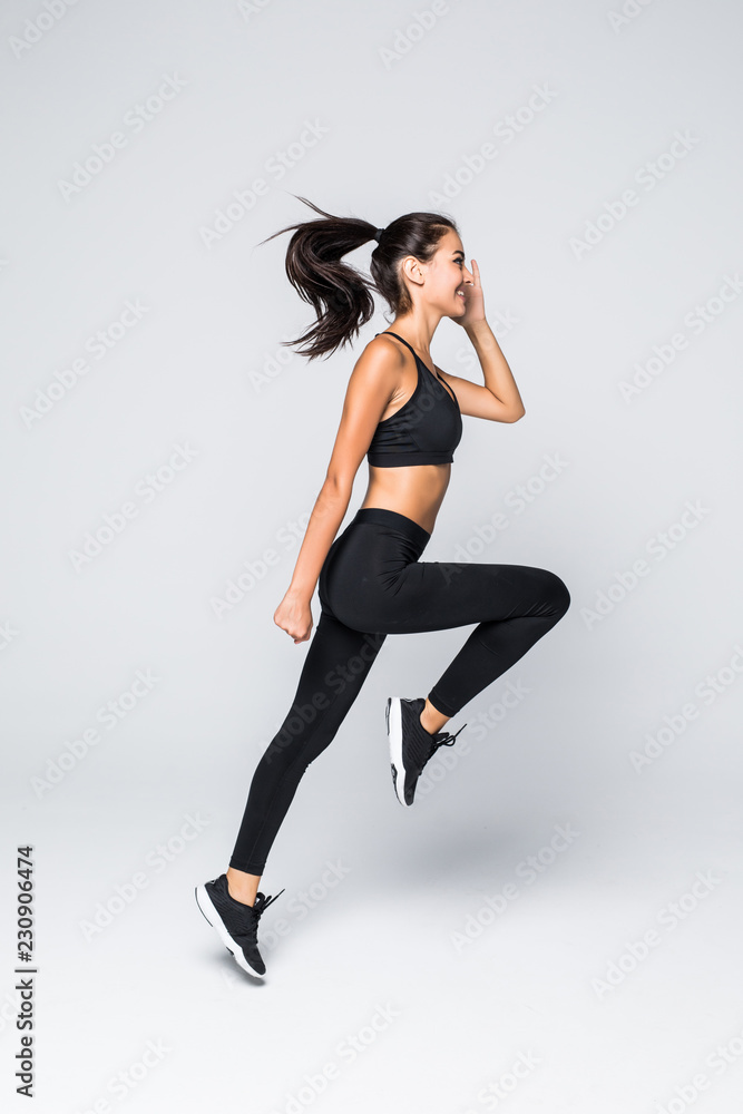 Full length of jumping fitness woman over gray background