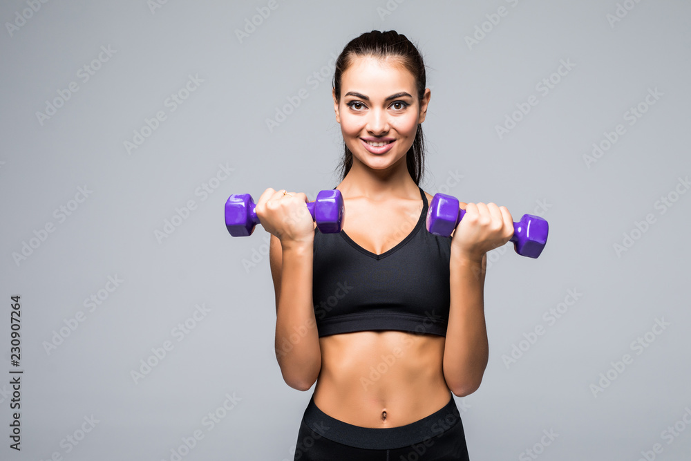 Sporty woman does the exercises with dumbbells on white background. Muscular woman in sportswear on white background. Strength and motivation. Sporty woman does the exercises with dumbbells on white background. Muscular woman in sportswear on white background. Strength and motivation.