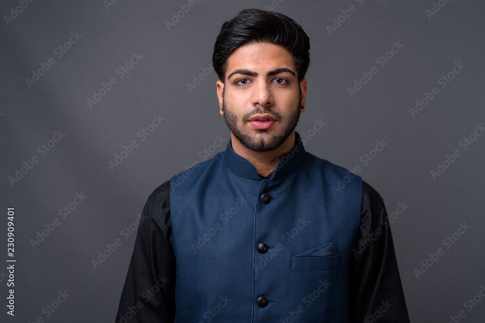 Obraz premium Young handsome Indian businessman against gray background