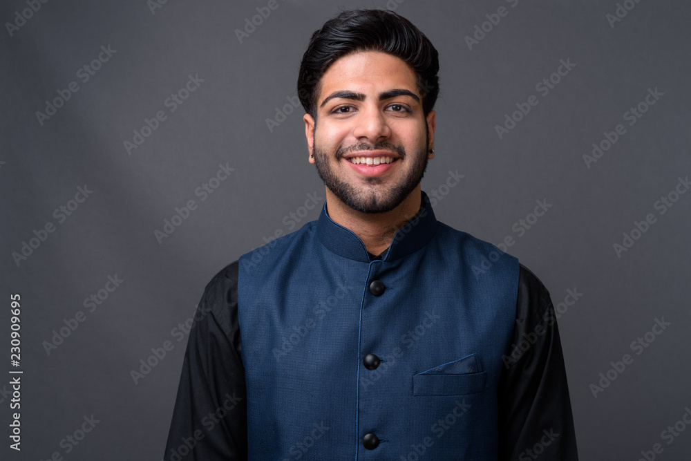 Obraz premium Young handsome Indian businessman against gray background