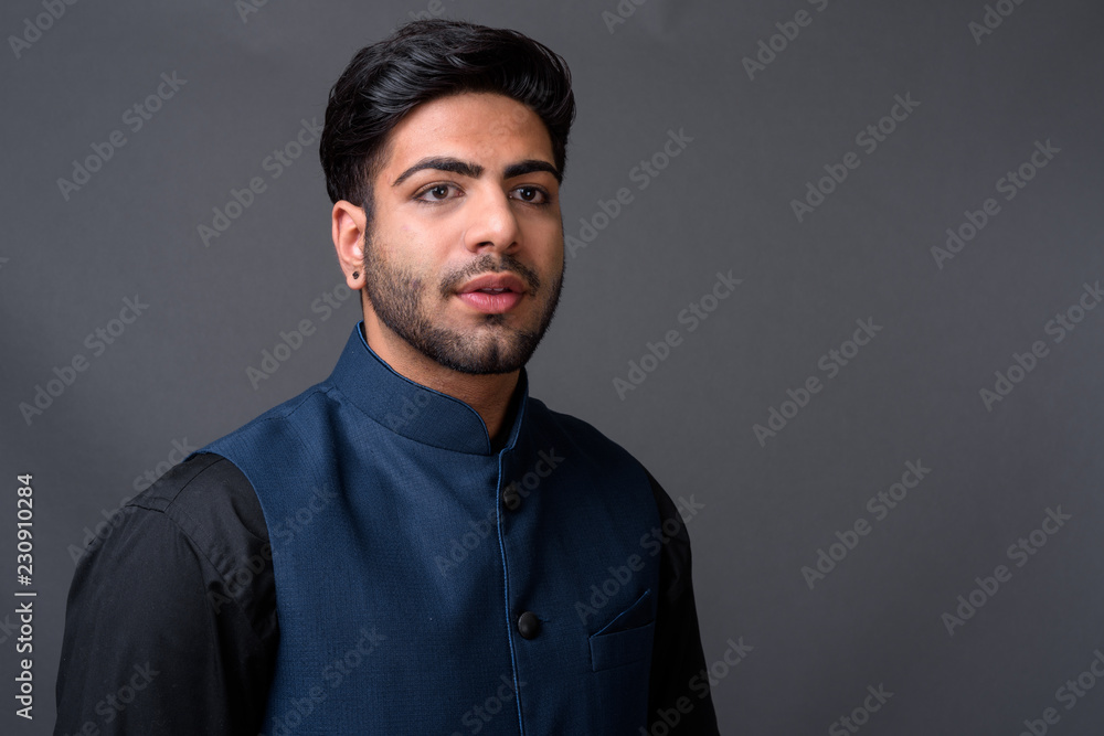 Fototapeta premium Young handsome Indian businessman against gray background