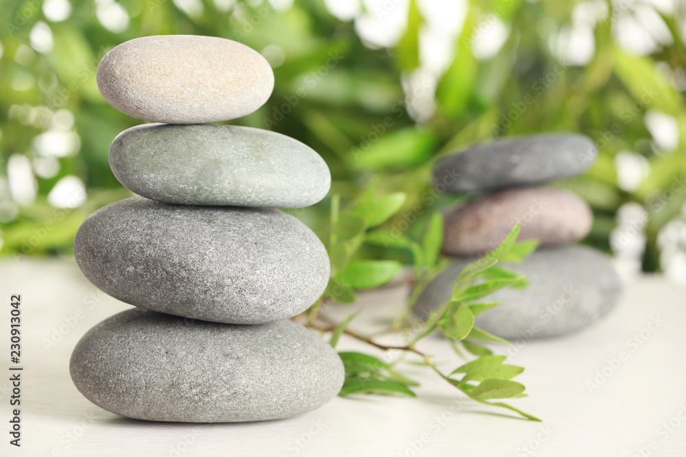 Spa stones and bamboo leaves on table against blurred background. Space for text Spa stones and bamboo leaves on table against blurred background. Space for text