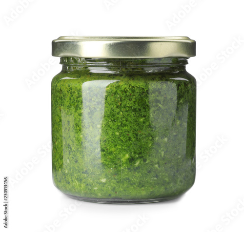 Homemade basil pesto sauce in glass jar on white background