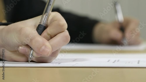 Close up of girls hands writing essays in an exam, classroom or exam hall.