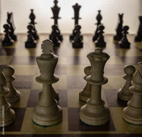 background. wooden chess pieces (white / black) placed on a chessboard