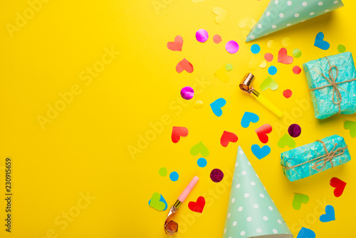 Birthday caps, blowers and confetti on a bright background