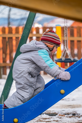 Boy climbing up the slide in winter