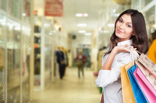 Young woman with shopping bags on background