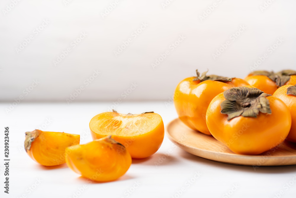 Half and sliced persimmon fruit on white table, healthy fruit