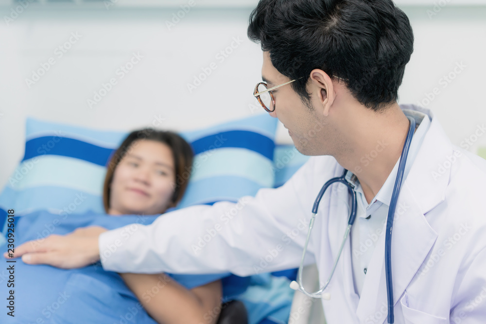 Asian young pregnant woman lying down talking and visit to her doctor man in a room. Asian young pregnant woman lying down talking and visit to her doctor man in a room.