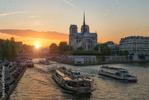 Notre Dame de Paris cathedral with cruise ship in Seine river in Paris, France. Beautiful sunset in Paris, France