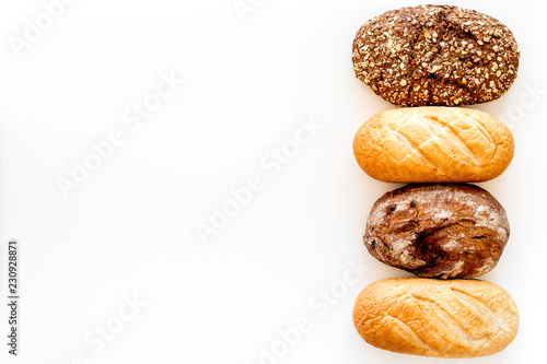 Loafs of white and brown homemade bread on white background top view copy space