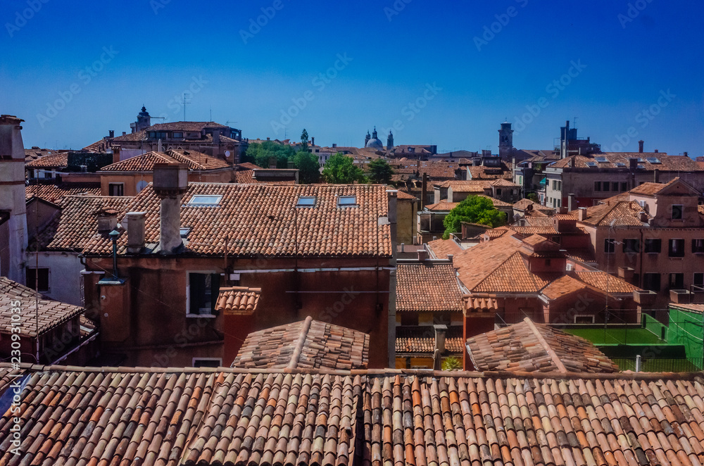 Venetian houses and rooftops under blue sky in Venice, Italy