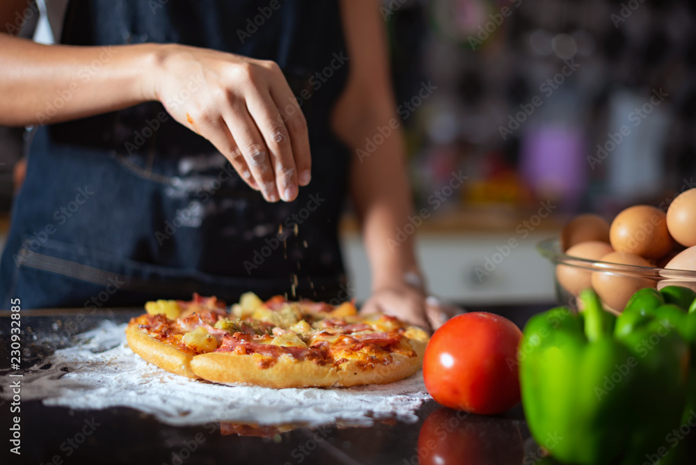 Closeup of  hand female wears apron,sprinkle with flour as prepares delicious pizza, going to make surprise for family and treat with tasty pastry, Baking concept.