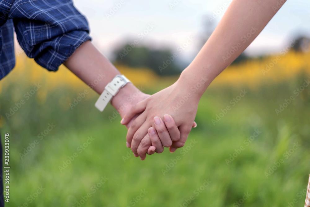 Rear view of two teens student together holding hand in hand Rear view of two teens student together holding hand in hand