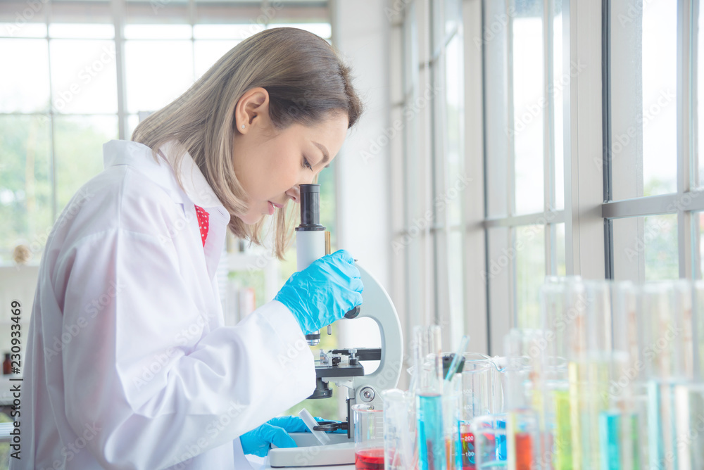 Beautiful asian scientist looking through a microscope in laboratory. Beautiful asian scientist looking through a microscope in laboratory.