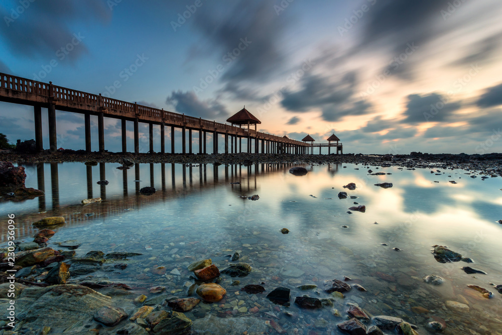 Fototapeta premium A Long exposure picture of golden sunrise with stone jetty