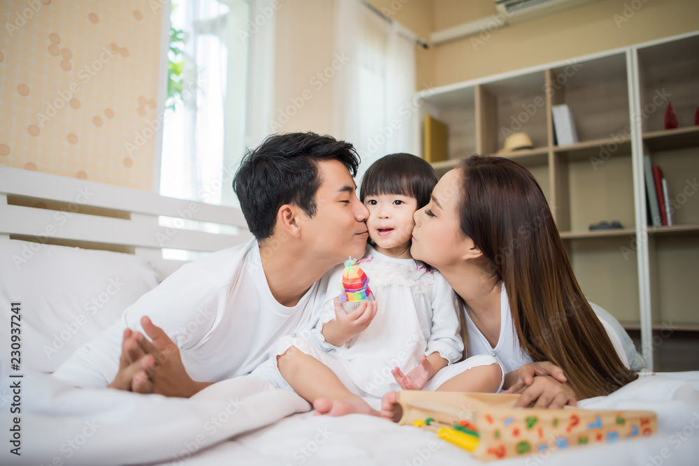 Happy child with parents playing in the bed at home Happy child with parents playing in the bed at home