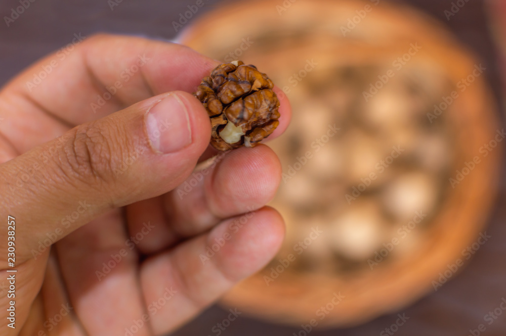 A person showing and offering a walnut kernel from a large bowl A person showing and offering a walnut kernel from a large bowl