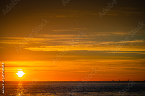 Large orange sunset as the massive sun sets into the horizon above the ocean, France © SpiritProd33