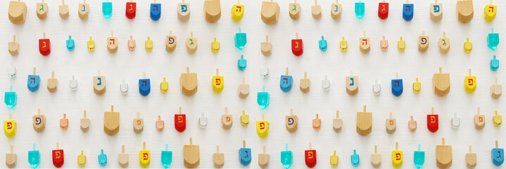 banner of jewish holiday Hanukkah with wooden dreidels colection (spinning top) over white background.