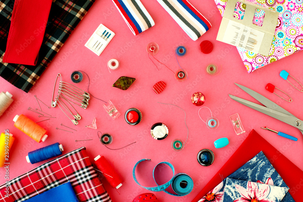 Obraz premium Items for sewing clothes on a pink background. View from above. Fabric, measuring tape, tailoring scissors, needles, buttons on a pink background for sewing clothes. Fashion and design.