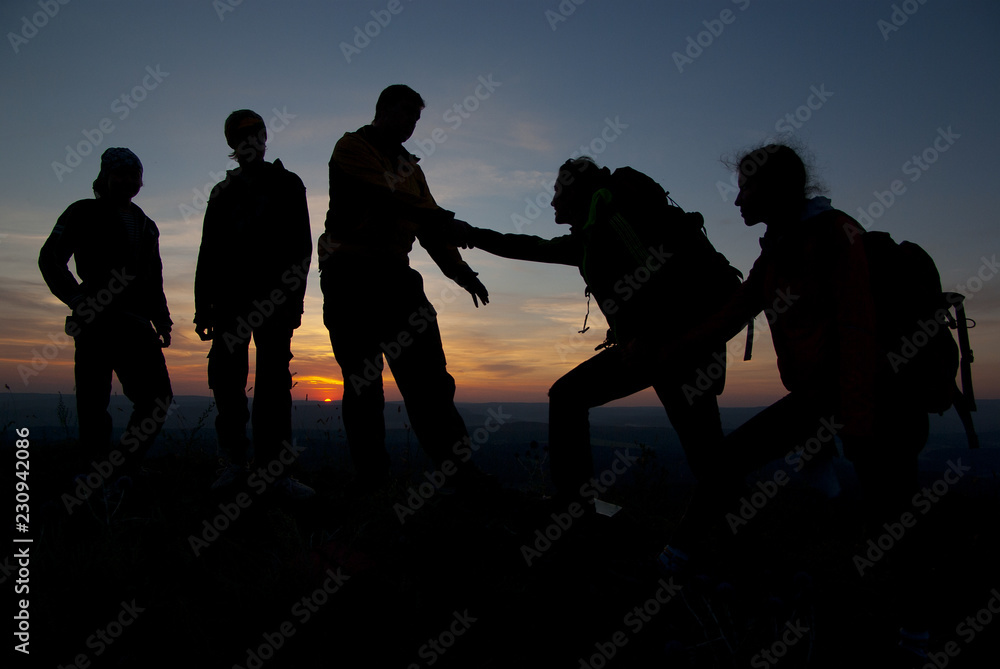 A group of tourists on top of a mountain at sunset.