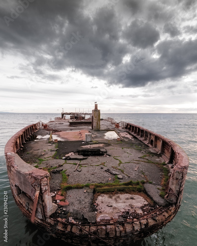 decrepit ship on ocean with cloudy sky photo