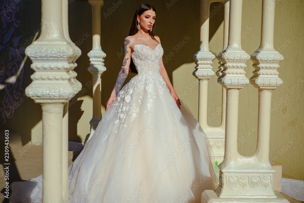 Fototapeta premium Happy bride before wedding. Beautiful wedding dresses in boutique. Wonderful bridal gown. woman is preparing for wedding. Elegant wedding salon is waiting for bride. Feeling grateful