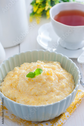 Milk corn porridge in a blue bowl for breakfast, selective focus