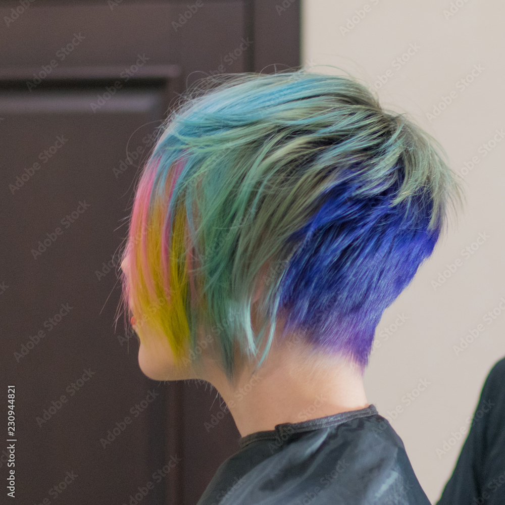 Naklejka premium Woman 30-40 smiles and made coloring of hair in different colors in a hairdressing salon. Change the image of a woman.