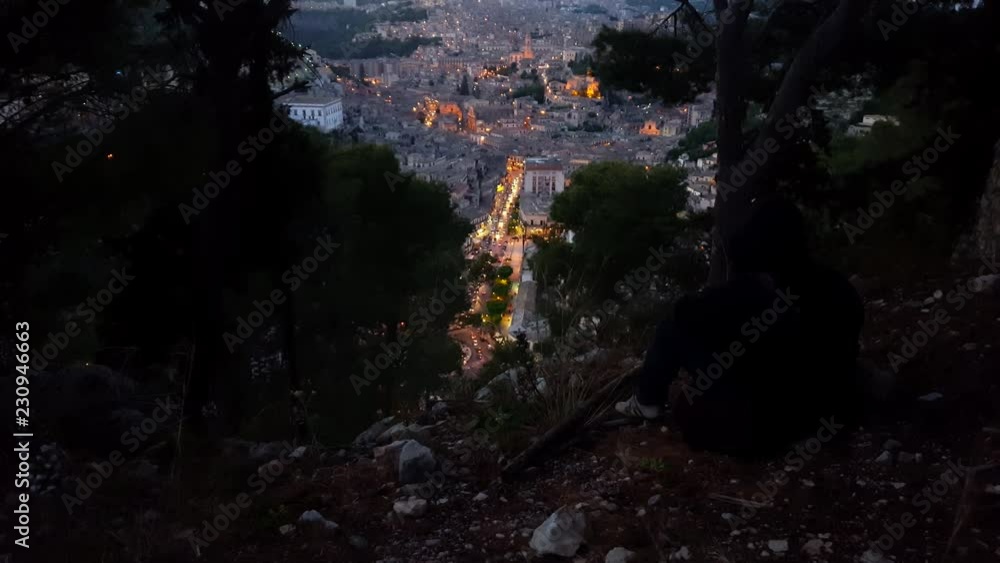 Modica in the Sicily - Italy nightfall timelapse. Man photographs urban hill landscape. Main street seen from the mountain. Modica in the Sicily - Italy nightfall timelapse. Man photographs urban hill landscape. Main street seen from the mountain.