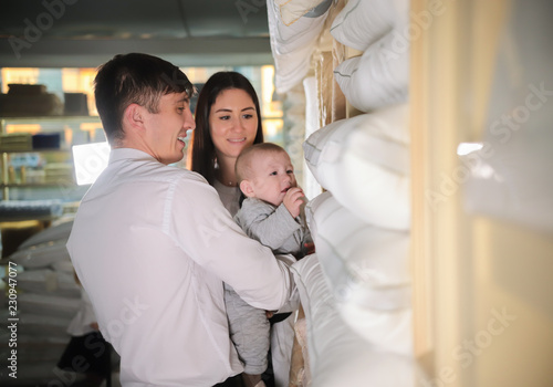 Young happy family on shopping. Married couple and a baby walking in textile shop