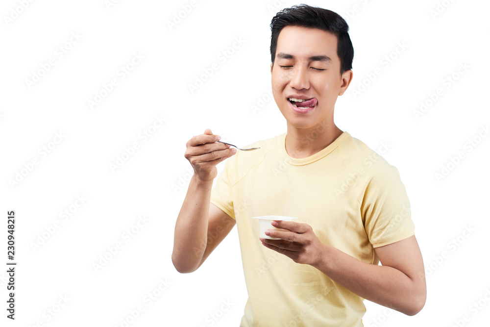 Young man licking lips after eating yogurt, isolated on white Young man licking lips after eating yogurt, isolated on white