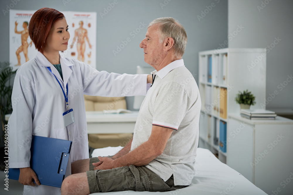 Obraz premium Smiling young female doctor reassurig aged patient