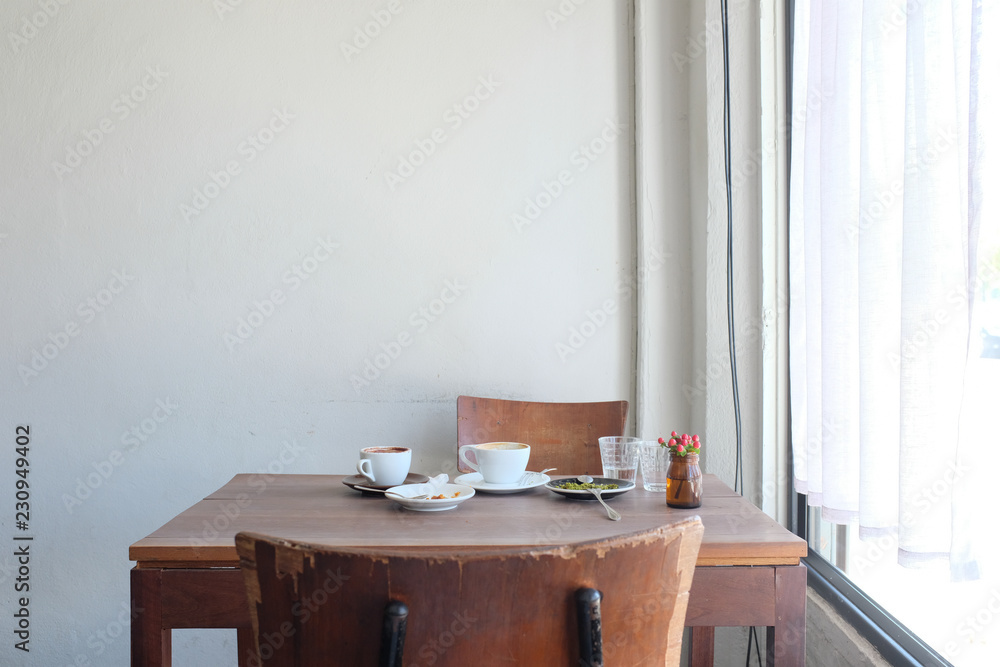 Φωτογραφία Wooden chair and wooden table with coffee cake water on white wall background in