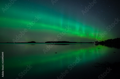 Northern lights dancing over calm lake in Faenebofjarden national park in Sweden