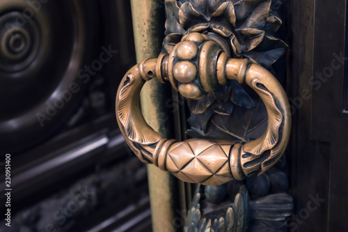 Antique figured bronze door knob on a massive carved wooden door
