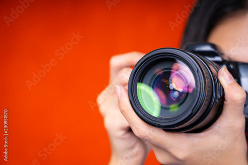 Photography background concept. Closeup of photographer using a camera on red background.
