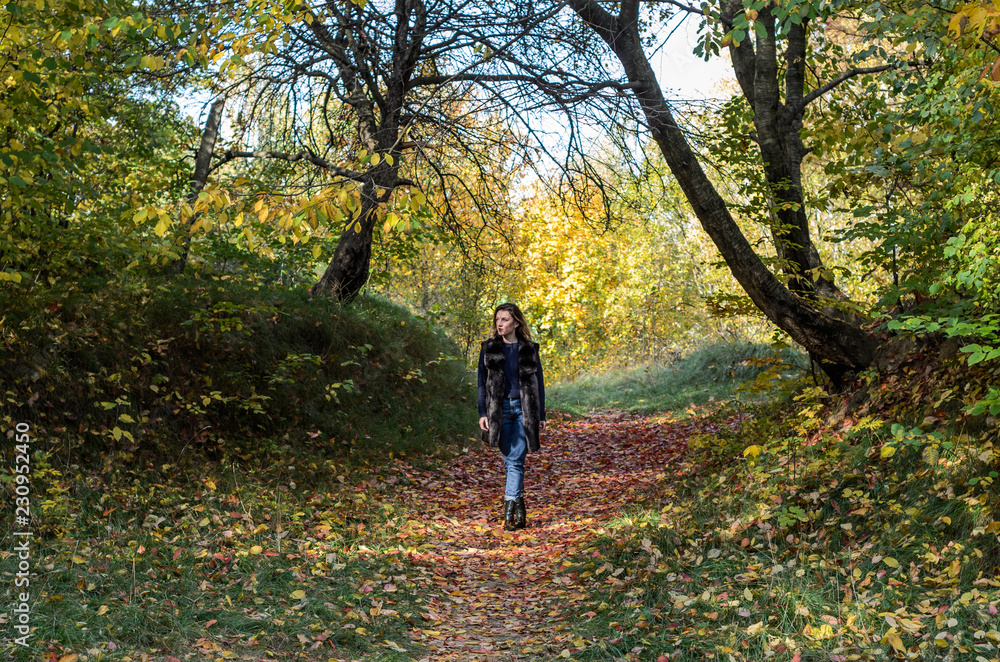 Young beautiful girl with long hair walks in the autumn forest