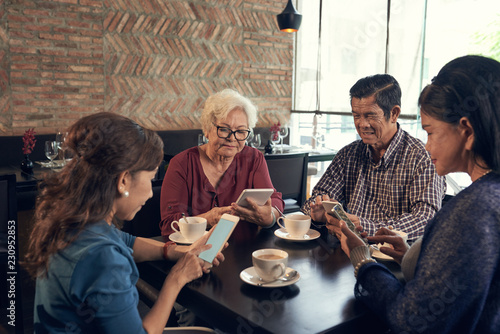 Senior peope using gadgets instead of talking with each other photo