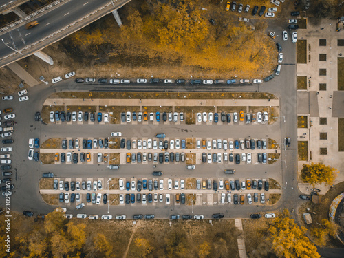 Outdoor parking lot or car park with rows of autos in urban landscape, aerial or top view